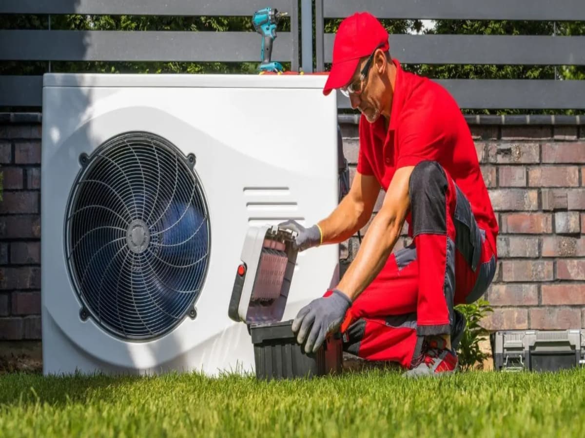 Technician installing an air-source heat pump outside a home